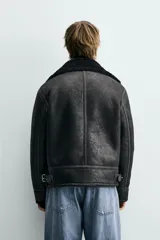 Cazadora de estilo biker con exterior de efecto cuero y forro interior de borreguillo. Presenta cierre frontal asimétrico con cremallera, cuello solapa con trabilla, bolsillos con cremallera y bajo ajustable con trabillas laterales.