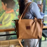 Cartera tipo tote de cuero natural color camel, con textura granulada. Cuenta con doble asa fija para llevar al hombro, correa larga ajustable y removible, cierre superior y bolsillo externo con cierre en la parte trasera.
