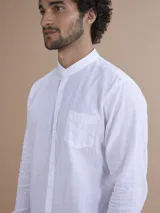 Camisa blanca de manga larga con cuello mao y cierre frontal de botones.