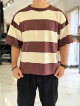 Remera de punto a rayas horizontales en tonos azul marino y beige, de manga corta y corte oversize. Presenta un gran número 15 rojo estampado en la espalda.