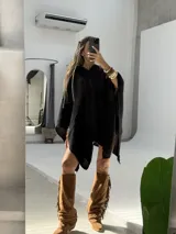 Poncho negro con capucha, confeccionado en tejido de punto abierto, con diseño amplio y caídas asimétricas.