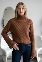 Sweater de punto acanalado color marrón, con cuello alto tipo tortuga y mangas largas con diseño acampanado.