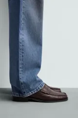 Mocasín de vestir fabricado en piel color marrón oscuro, con detalle de antifaz en el empeine, plantilla de piel y suela a contraste con ligero tacón.