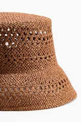 Sombrero de paja color marrón con diseño trenzado y calado, copa plana y ala ancha inclinada.