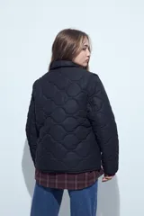 Campera acolchada de color negro con diseño capitoneado, cierre frontal con botones y cuello clásico.