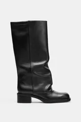 Bota alta de piel estilo biker, color negro, con diseño slouchy y puntera semi cuadrada. Cuenta con tacón bajo y ancho.