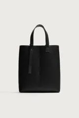 Bolso shopper de hombro en color negro, con diseño minimalista y liso. Cuenta con compartimento principal con cierre magnético y un bolsillo interior plano.
