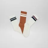 Pack de tres pares de medias de caña media, una color blanco con dos rayas horizontales azul marino y bordó, otra color blanco con dos rayas horizontales verde y azul marino, y otra color marrón con dos rayas horizontales blancas.