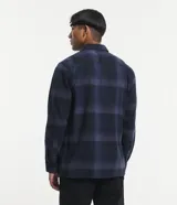 Camisa de manga larga con diseño de cuadros en tonos marrones, confeccionada en algodón. Presenta cuello camisero, cierre frontal con botones y un bolsillo en el pecho con botón.