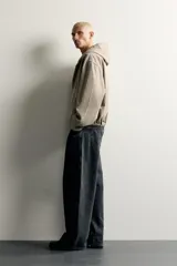 Cazadora de denim de algodón color negro con efecto lavado, de corte relaxed fit, manga larga y capucha. Cuenta con cierre frontal de cremallera, bolsillos frontales tipo canguro y acabados con elástico en puños y cintura.