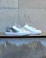 Zapatillas plateadas de cuero con cordones grises y suela blanca.