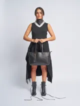 Cartera tipo shopper color negro, de cuero sintético, con doble asa de hombro, cierre superior y doble compartimento interno.