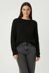Sweater de punto liso con cuello redondo a la base, diseño holgado y mangas largas.