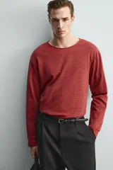 Camiseta de manga larga con cuello redondo, corte relajado y diseño de rayas horizontales en tonos rojo y negro.