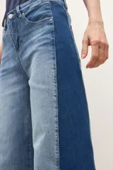Jean wide leg bicolor en tonos de gris oscuro, con paneles laterales más oscuros y ruedo deshilachado.