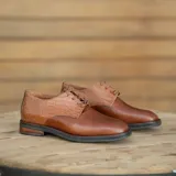 Zapato mocasín de cuero vacuno color negro, con cordones y punta redonda. Tiene taco de madera foliado en cuero de 2,5 cm y entre suela de goma de 1 cm.