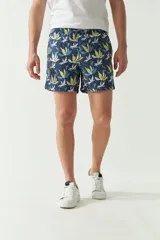 Short de baño con estampado botánico en tonos turquesa, blanco y azul. Presenta cintura elástica con cordón ajustable, dos bolsillos laterales y uno trasero, además de un logo bordado en la pierna.