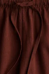 Pantalón marrón de tejido liviano con lino en la trama. Modelo de tiro bajo con elástico revestido y cordón para ajustar en la cintura, bolsillos al bies y piernas rectas.