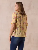 Blusa de gasa estampada con cuello a la base, escote en V plisado y lazo de ajuste. Delantera con detalles en puntilla y manga corta con puño fruncido.
