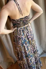 Vestido largo de satén color marrón con estampado de lunares blancos. Presenta un diseño cut-out en la cintura, escote halter con detalle de mostacillas y terminaciones con puntilla negra en el top.