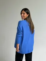 Sweater de tejido de punto color azul, con escote en V, manga larga con puños acanalados y diseño holgado con costura central vertical y ruedo asimétrico.