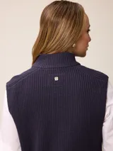 Chaleco de tejido de punto en color gris, con cierre frontal completo, cuello alto y dos bolsillos delanteros tipo parche.