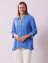 Camisa celeste de textura arrugada, con cuello clásico, cierre frontal con botones y mangas 3/4 con trabilla.