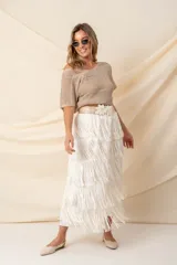 Pollera midi color vainilla, de gasa plisada con flecos y cintura elastizada.