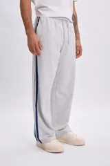 Pantalón deportivo gris melange con tiras laterales oscuras y corte recto.