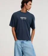 Pantalón de jean color celeste, modelo barrel, de tiro medio con trabillas para cinto, cierre frontal con botón y cremallera, bolsillos, recortes laterales y pinzas en las rodillas.