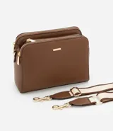 Bolso bandolera de tamaño mediano confeccionado en poliuretano color marrón. Presenta tres compartimentos independientes con cierre de cremallera, herrajes metálicos dorados y una correa de hombro ajustable de cinta tejida bicolor.