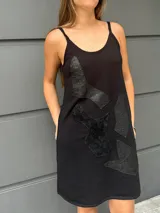 Vestido corto negro de algodón con breteles finos y apliques de cuero labrado. Corte suelto.