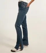 Pantalón bootcut de jeans azul con cintura alta, trabillas y cierre con botón y cremallera. Posee bolsillos delanteros y traseros, y detalle de encaje en el lateral de la parte baja.