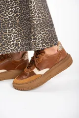 Zapatillas bajas de cuero color marrón con detalles en gamuza color tostado y talón en cuero dorado.