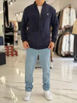 Campera azul marino de felpa con cierre frontal completo, cuello mao, bolsillos tipo canguro y logo bordado en el pecho.