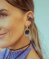 Aros colgantes dorados con dije circular de resina color turquesa, bordeado con strass. El arito es de acero quirúrgico.