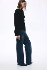 Jean de tiro alto con corte wide leg, confeccionado en denim rígido de lavado azul clásico. Presenta diseño de cinco bolsillos, cierre frontal con botón y ruedo desflecado.