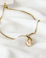 Collar dorado con cadena de eslabones pequeños y dije de caracol con detalles en marrón y blanco.