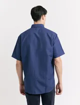 Camisa de manga corta azul con estampado de lunares blancos, cuello abotonado y bolsillo en el pecho.