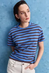 Remera de calce relajado con diseño a rayas horizontales blancas y verdes, hombros caídos y mangas amplias con vuelta. Presenta cuello redondo y ruedo trasero levemente más largo.