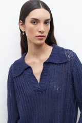 Sweater de punto calado en color azul, con cuello polo y escote en V. Presenta mangas largas con puños rectos y un diseño de tejido vertical.