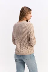 Buzo de punto negro con diseño de trenzas en relieve, cuello redondo y mangas largas.