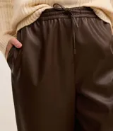Pantalón zanahoria de cuero sintético color marrón, con cintura alta elástica ajustable con cordón.