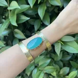 Pulsera rígida dorada con piedra ágata ovalada color verde agua.