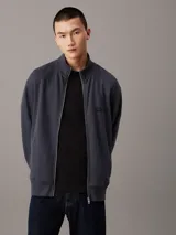 Sweater azul con textura tipo waffle, cuello alto, cierre frontal con cremallera metálica, puños y bajo acanalados, y logo pequeño en el pecho.