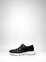 Zapato cerrado tipo zapatilla de cuero natural negro, combinando sectores lisos y texturados, con aperturas laterales y cierre de velcro. Cuenta con suela blanca liviana y anatómica.