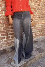 Jean de corte wide leg con diseño de paneles en diferentes tonos de gris y negro. Presenta cierre frontal con cremallera expuesta y costuras decorativas que crean un efecto de contraste.
