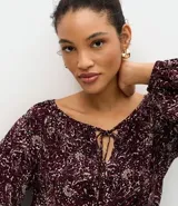 Blusa de viscosa con estampado de follaje, escote canoa con lazo delantero y mangas largas abullonadas.