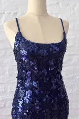 Vestido corto ajustado de tirantes finos, completamente cubierto de lentejuelas azul oscuro o violeta brillante.
