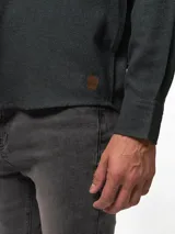 Camisa de franela color azul marino, de manga larga, con cuello abotonado, un bolsillo frontal y cierre de botones.